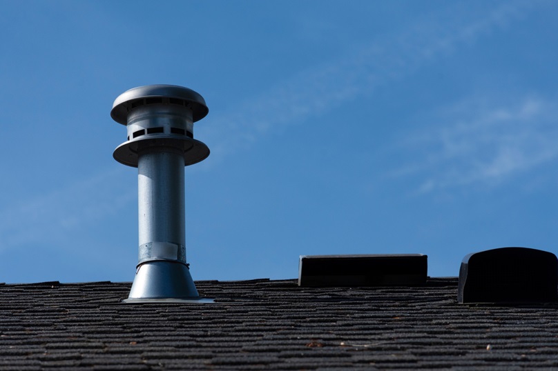 Imagine stepping into your home on a chilly winter evening or a sweltering summer day and feeling the right level of comfort—neither too cold nor too hot. This ideal scenario isn't just about your heating or cooling system working overtime; it's also about something often overlooked: roof ventilation. Proper roof ventilation is crucial for maintaining not just the temperature inside your home but also the health of your roof itself. Without adequate ventilation, your attic can become a breeding ground for moisture buildup and excessive heat, leading to problems like mold, rot, and ice dams that can compromise your roof’s integrity. In this article, the Intelligent Design Corp team explores how a well-ventilated roof functions, the common issues with poor ventilation, and practical tips to ensure your roofing system remains sound and efficient. Why is Proper Roof Ventilation Crucial? Adequate ventilation helps to reduce heat accumulation in the attic. If not properly vented, this heat can cause the shingles to deteriorate prematurely, leading to higher energy costs as air conditioning systems work harder to cool the home. Proper ventilation in the winter helps to minimize the formation of ice dams. These occur when heat escapes from the home's warm interior, melts the snow on the roof, and refreezes at the eaves, potentially leading to water damage. Ventilation is also crucial for preventing moisture accumulation that can lead to mold growth and wood rot. By allowing a continuous flow of air, moisture is expelled, safeguarding the roof’s materials and the overall structure of the attic. This extends the roof's life, ensuring a healthier living environment and improving indoor air quality. How to Assess Your Roof’s Ventilation Needs Assessing your roof's ventilation needs is crucial to ensuring its longevity and functionality. There are several key steps to identify and prevent problems, and here's how! Do an Inspection Inspect the attic space for inadequate ventilation, such as moisture condensation, mold growth, or an unusual heat build-up. These signs indicate the airflow is insufficient to keep the attic dry and cool. Additionally, check for blocked or covered vents that hinder proper air circulation. It's essential to ensure that both intake and exhaust vents are clear of obstructions to facilitate effective air exchange. How Much Ventilation Do You Need? Calculate the ventilation area needed for your roof. This can typically be done by following the general guideline of having at least one square foot of vent area for every 150 square feet of attic space. However, this ratio can vary depending on the climate and the specific design of your house. It is highly recommended that you consult with a roofing professional who can perform a detailed assessment and provide tailored advice based on your roof’s characteristics and local building codes. How Many Vents are Required? Consider the type and number of vents installed. An ideal balanced system of intake and exhaust vents should be installed. Intake vents should be placed at the roof’s lowest point to draw in cool air, while exhaust vents should be located near the ridge or peak to expel warm, moist air. This setup promotes a continuous flow of air, helping to regulate temperature and humidity levels efficiently. What are the Consequences of Poor Roof Ventilation? Poor roof ventilation can lead to several significant issues that compromise your home's structural integrity and efficiency. The most common ones to be aware of are: Overheating One of the most immediate effects of inadequate ventilation is overheating attic space during the summer. This excessive heat can damage the roof shingles, causing them to warp or deteriorate prematurely. Over time, this can lead to frequent and costly repairs or even a full roof replacement earlier than expected. Moisture Issues In addition to heat damage, poor ventilation can create a perfect environment for moisture buildup. This moisture can lead to the growth of mold and mildew, which not only affects the attic's structural components but can also pose health risks to the inhabitants by degrading indoor air quality. Furthermore, during colder months, inadequate ventilation can contribute to the formation of ice dams on the roof's edge. These dams can cause water to back up and leak into the home, potentially damaging walls, ceilings, and insulation. Decreased Energy Efficiency Poor roof ventilation increases energy consumption. When heat is trapped in the attic, air conditioning systems have to work harder to cool the home, leading to higher energy bills. Proper ventilation helps maintain an energy-efficient home by reducing the cooling load during warmer months. How Can Improved Ventilation Extend the Life of Your Roof? Effective ventilation ensures a balance between air intake and exhaust, which helps maintain an optimal temperature and moisture level in the attic. This balance is key to preventing the common issues that can lead to premature roof degradation. Proper ventilation regulates attic temperatures, preventing roofing materials from overheating in the summer and reducing the risk of ice dam formation in the winter. Overheated shingles can deteriorate quickly, and ice dams can cause water to back up under shingles, leading to leaks and structural damage. Efficient ventilation helps avoid these extremes, preserving the integrity of the roof materials. Moreover, ventilation helps reduce moisture accumulation in the attic, which can cause wooden structures to rot and metal components to corrode. It also prevents the buildup of harmful mold and mildew, which weakens structural materials and reduces the overall air quality inside your home. What Types of Roof Vents Are Available? Several types of roof vents are available, each designed to suit different architectural styles and functional needs. The main categories include: Ridge Vents Ridge vents are installed along the roof's peak, providing continuous airflow along the ridge line. Soffit Vents Soffit vents are placed in the eaves to allow fresh air into the attic. Gable Vents Gable vents are located at the end walls of the attic and are used primarily in homes with gable roofs. Ventilators Powered attic ventilators, or attic fans, use electric power to actively push hot air out of the attic. These are especially useful in regions with high temperatures. Enhancing Roof Health Through Effective Ventilation Through proper ventilation techniques, homeowners can prevent the common issues of heat buildup and moisture accumulation and the subsequent damage they can cause. Regular assessments and the right choice of vents tailored to your home's needs can significantly contribute to a durable and reliable roofing system. Intelligent Design Corp is your local roofing specialist. Whether you need a new installation, upgraded ventilation, siding, or window services, we have you covered! To schedule an appointment, give us a call or reach out online today.